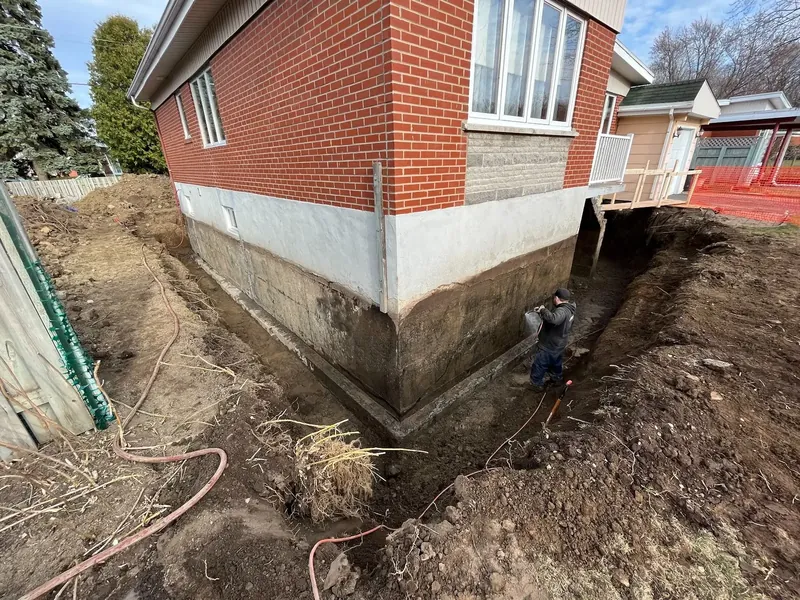 Fondation dégagée jusqu’à la semelle le long d’une maison de brique
