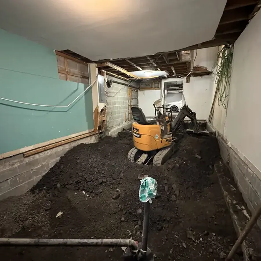 Mini-pelle dans un garage pour sortir le remblai sous la dalle